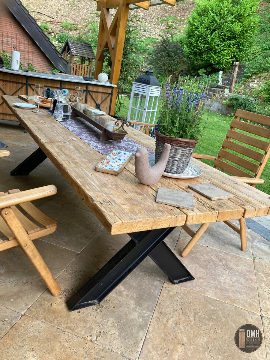 Handgefertigter Gerüstbohlentisch von OMH Wood & More mit massivem X-Stahlgestell auf einer Terrasse